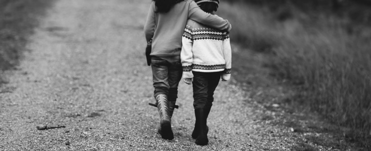 Black and white photograph of a parent comforting a young child of 10 years old.