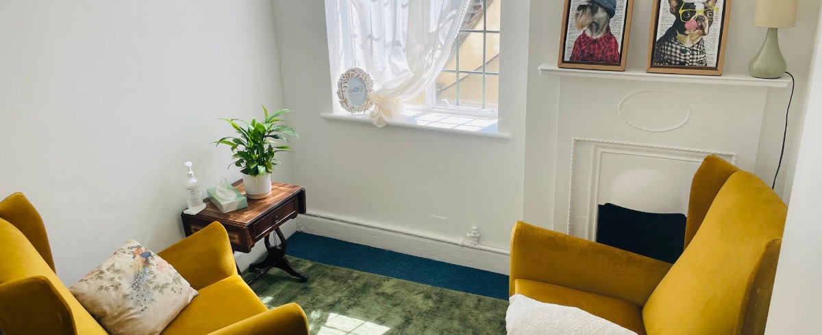 A white room with two comfortable looking chairs upholstered in honey coloured velvet material.